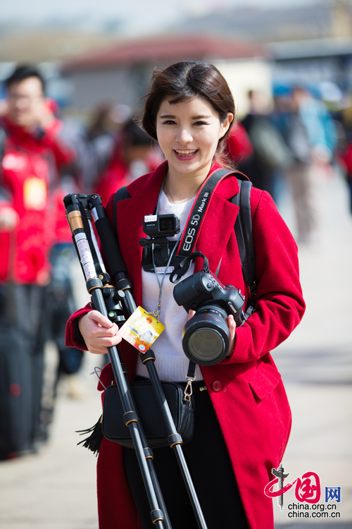 2016年兩會(huì)，人民大會(huì)大堂前，一位笑容燦爛的紅衣女記者正步入大會(huì)堂。中國(guó)網(wǎng) 鄭亮 攝
